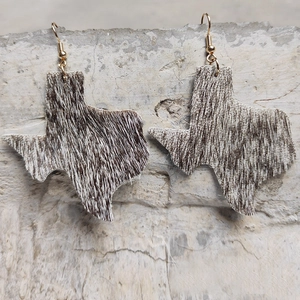 Close-up of cowhide Texas state earrings with hair-on leather and gold hooks