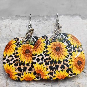 Dettaglio di orecchini di zucca in pelle con motivo girasole e leopardo su pietra