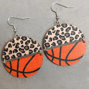 Macro shot of circular leopard print and orange basketball textured leather earrings