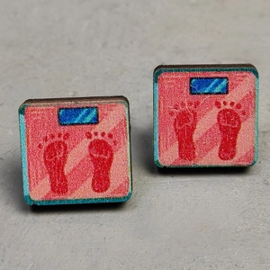 Detail view of square wooden stud earrings with pink digital scale and footprint pattern