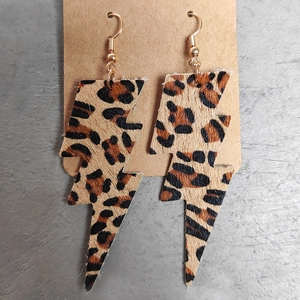 Detalle macro de pendientes en forma de rayo con textura de leopardo en piel sintética