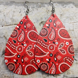 Dettaglio di orecchini a goccia in pelle rossa con motivi paisley neri e bianchi