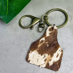 Western cowhide leather ear-tag keychain with brown brindle fur and bronze hardware