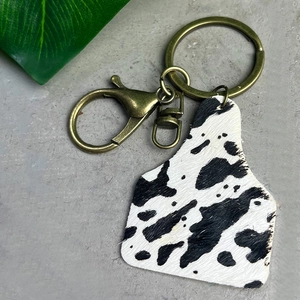 Western cow print leather ear tag keychain with bronze lobster clasp and hair-on texture