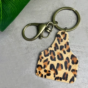 Macro detail of western ear tag keychain with leopard print fur and antique bronze hardware
