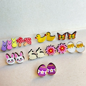 Close-up of Easter themed wood stud earrings featuring rabbits, mushrooms and butterflies