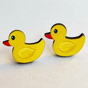 Macro shot of cute yellow duck stud earrings with red beak and matte texture
