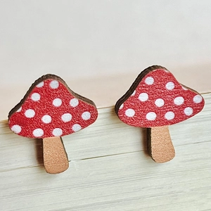 Close-up of handmade wooden mushroom earrings with red and white polka dot pattern