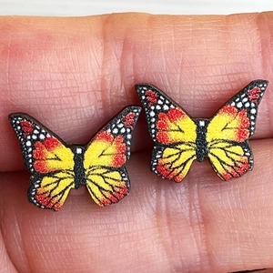 Vibrant butterfly stud earrings with red and yellow gradient wings held on a hand