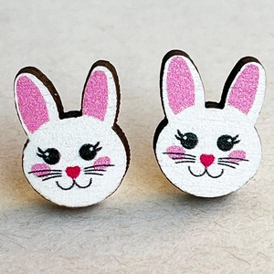 Macro view of cute white wooden rabbit stud earrings with pink ears for Easter
