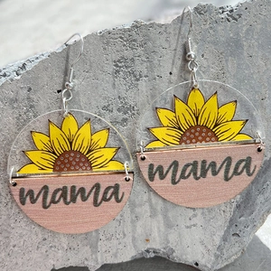 Detail of acrylic sunflower mama earrings with wooden half-circle on a stone surface