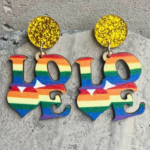Love wood earrings with rainbow stripes and yellow sequins on grey stone background