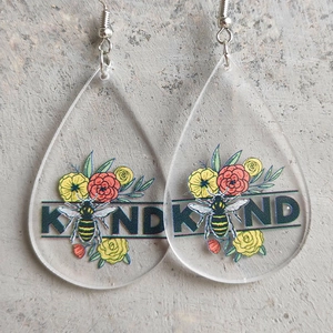 Detail of drop-shaped acrylic earrings with floral patterns and KIND printed text