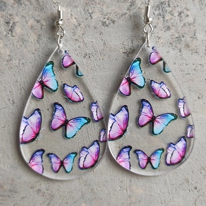 Macro shot of teardrop acrylic earrings with colorful butterfly prints and silver hooks
