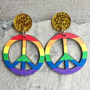Close-up of rainbow peace sign wooden earrings with gold glitter resin accents