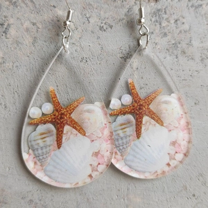 Macro detail of teardrop acrylic earring with starfish, shells and white pearls