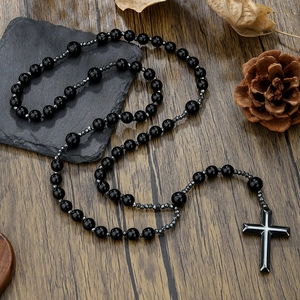 Detailed shot of black beaded necklace with cross pendant on rustic wooden background