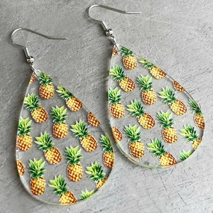 Macro detail of teardrop acrylic earrings with vibrant pineapple pattern and metal hooks