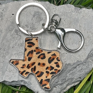Close-up of leopard print Texas map leather keychain with silver lobster clasp on stone