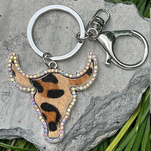 Western leopard cow head keychain with iridescent rhinestones on a natural stone background