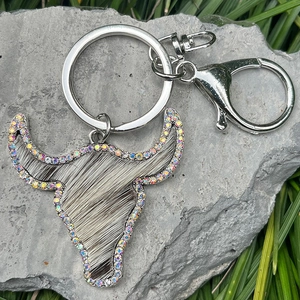 Detailed close-up of a western bull head keychain with rhinestones on a rustic rock surface