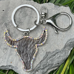 Detail of steer head keychain with rainbow rhinestones and cowhide on natural rock