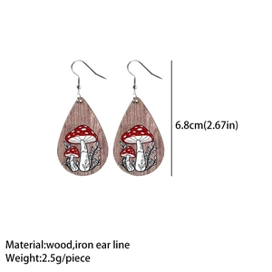 Detail view of teardrop wooden earrings featuring red mushroom prints and size specifications