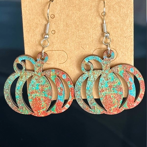 Detail of colorful pumpkin earrings with artistic paint finish on brown craft card