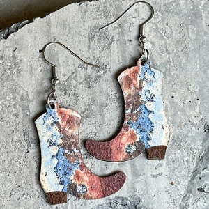 Pendientes de madera de botas vaqueras con motivos florales sobre fondo de piedra