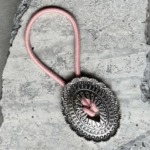 Détail de l'élastique rose avec ornement ovale en métal argenté de style vintage