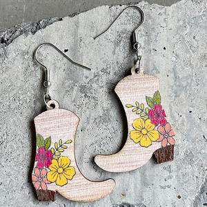 Pendientes de madera con forma de bota de vaquero y flores sobre fondo de piedra