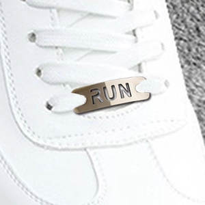 Macro detail of 'RUN' engraved metal shoe lace buckle charm on white sneakers
