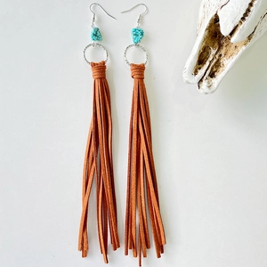Detail of bohemian brown leather tassel earrings with turquoise stones and hammered rings