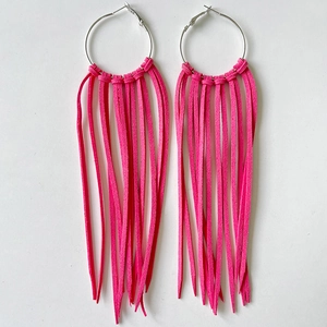 Close-up of pink fringe tassel earrings with large silver rings in western cowboy style