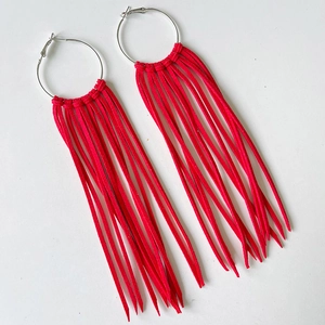 Detail of red tassel hoop earrings with silver rings in Western cowboy style