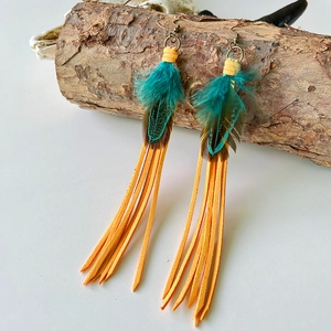 Detail of bohemian long feather earrings with yellow leather tassels on wood base