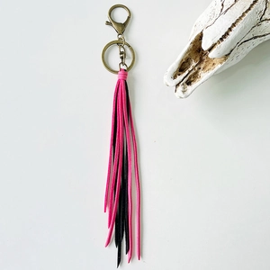 Detail of pink and black fringe keychain with vintage bronze clasp and white skull decor