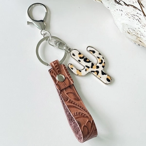 Detailed view of brown embossed leather wristlet and leopard print cactus pendant