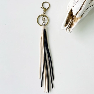 Detail of vintage bohemian tassel keychain with dual-tone leather and bronze metal clasp