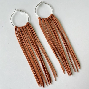 Macro view of oversized silver hoops with dense terracotta brown suede fringe details