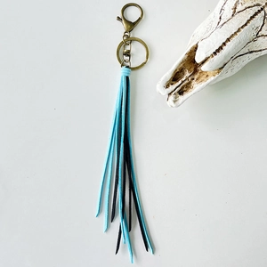Detail of vintage boho keychain with sky blue and black tassels and bronze clasp