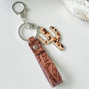Macro view of leather keychain with embossed leaf pattern and leopard cactus charm