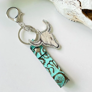 Detail of western cow skull keychain with rhinestones and turquoise embossed leather strap