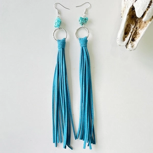 Detail of western turquoise drop earrings with vibrant blue leather fringe and metal rings