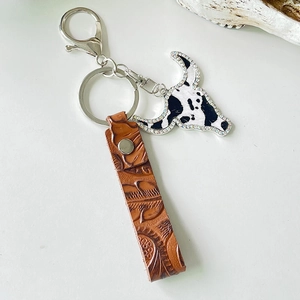Detail of red-brown leather keychain with embossed pattern and sparkling rhinestone bull head