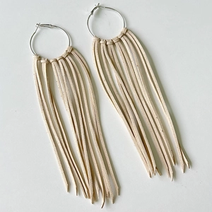 Detail of bohemian silver hoop earrings with long off-white suede fringe tassels