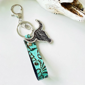 Close-up of western leather keychain with turquoise floral embossing and rhinestone bull head