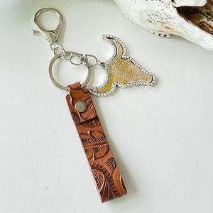 Close-up of brown embossed leather strap with rhinestone bull head keychain charm