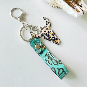 Detail of western cow skull keychain with leopard print and green embossed leather strap
