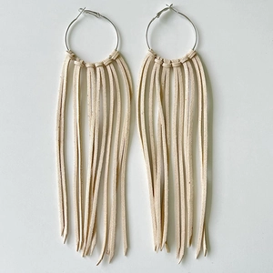 Detail of silver hoop earrings featuring soft beige leather fringe tassels and fine texture